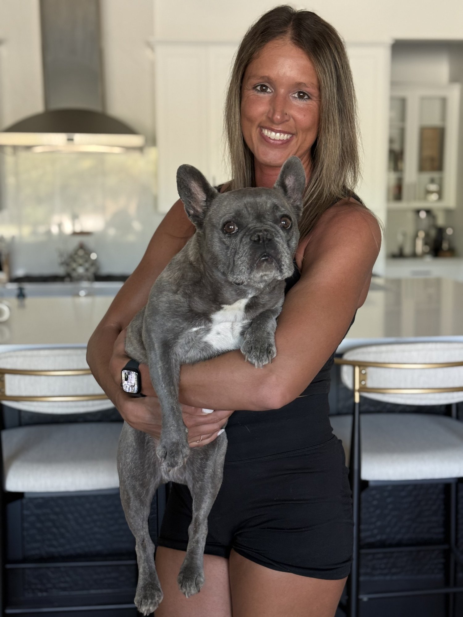 Jen, owner of Desert Paws AZ, holding her French Bulldog Tula at home in Queen Creek Arizona